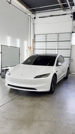 White Tesla Model 3 parked in a bay at the Phantom Tint shop for windshield and glass replacement