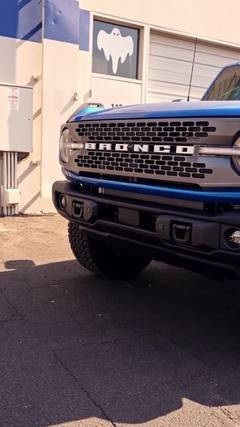 Ford Bronco with a blue-striped front end at the Phantom Tint shop, getting paint protection film